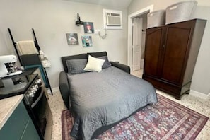 A bedroom with a bed, a dresser, a desk, and a wardrobe. - New Cottage + Monthly + Fire Pit + Outdoor Kitchen (Dallas)