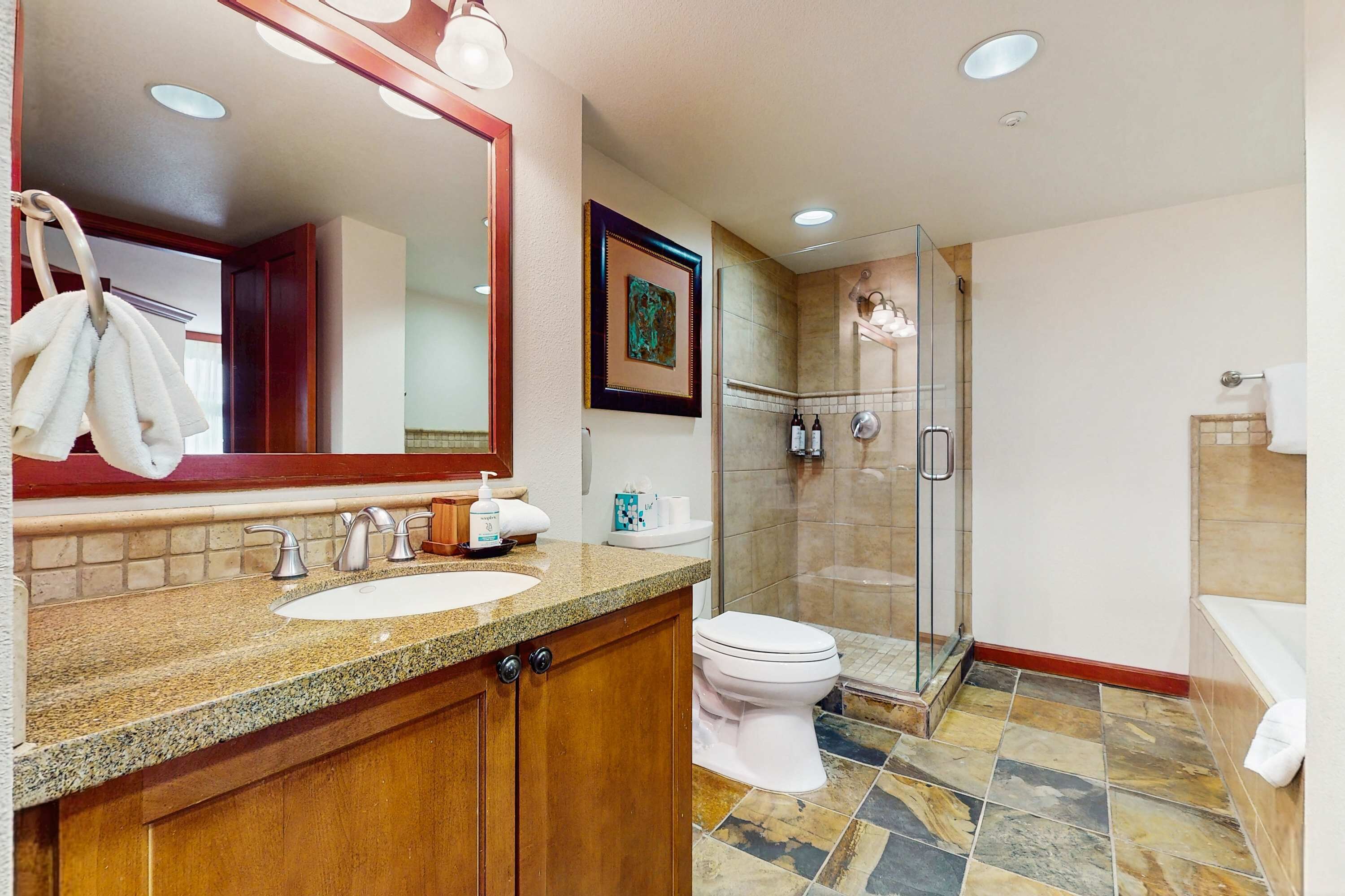 A bathroom with a sink, toilet, and shower area.