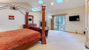 Ein Schlafzimmer mit einem großen Bett, einem Deckenventilator, einem Fernseher und einem Balkon.