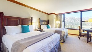 A hotel room with two beds, a dining table, a chair, a TV, and a large window with a mountain view. - Everline Resort & Spa Ski-in-ski-out condo with elevator, pool, hot tub, & spa (Olympic Valley)
