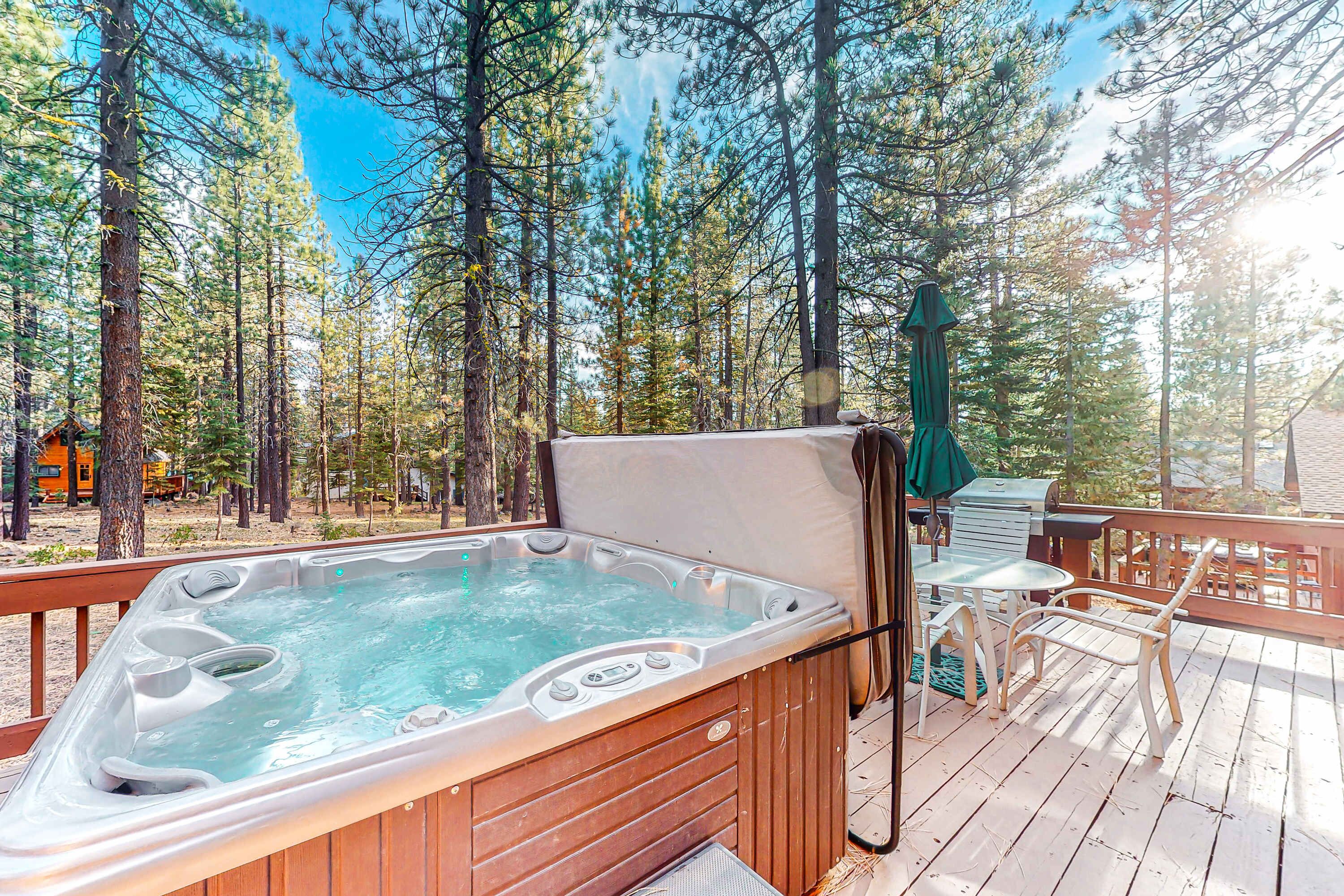 Un jacuzzi en una terraza de madera rodeado de árboles.