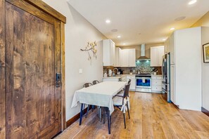 Una cocina moderna con armarios blancos, una isla central y un comedor con mesa y sillas.