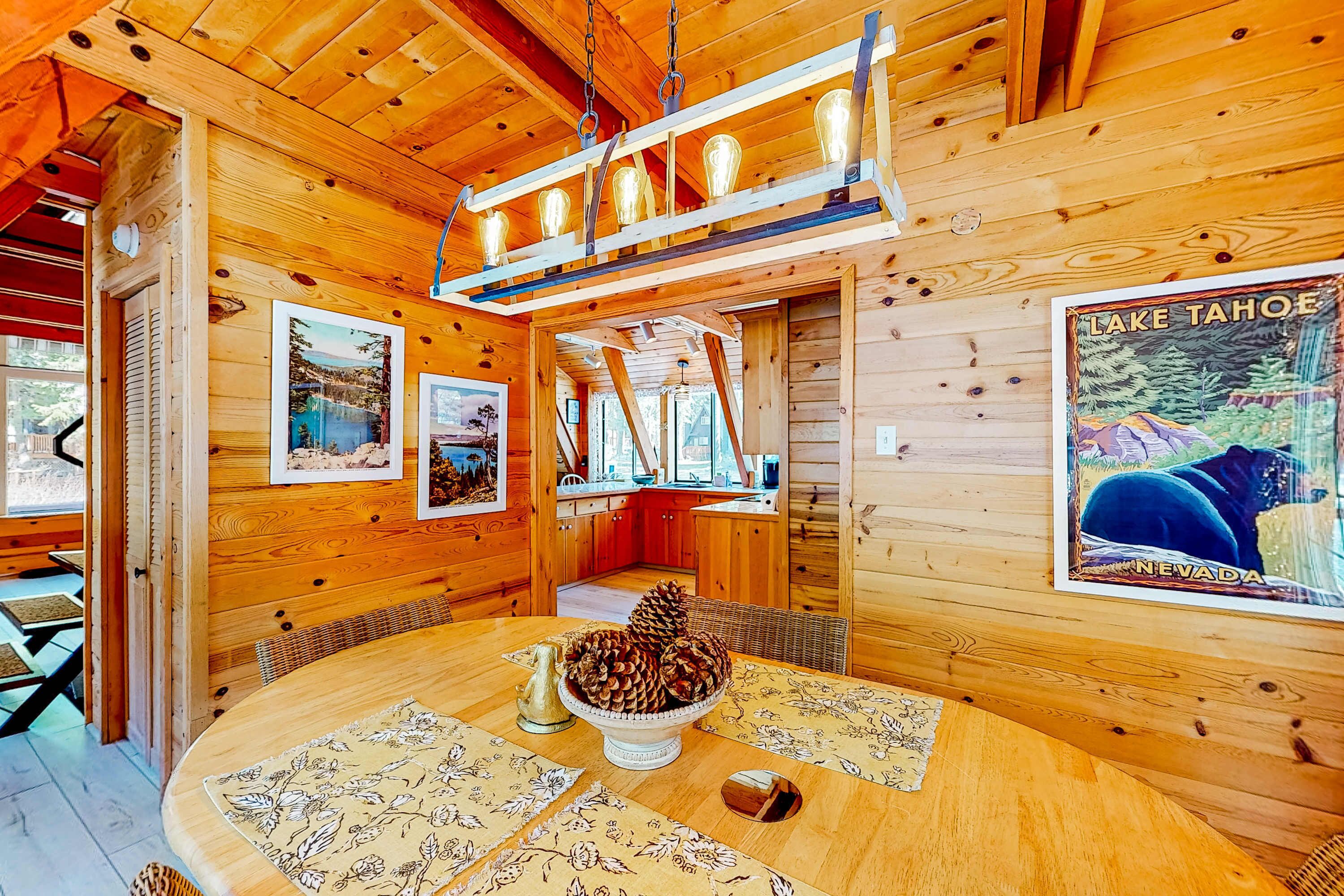 En inredning med trädetaljer, ett matbord, en bordsdekoration i form av ett kott, inramade bilder och en affisch med motiv från Lake Tahoe.