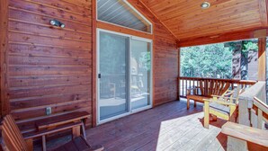 A wooden deck with benches and a sliding glass door leading to a covered patio area. - Mountain Home with Access to Shared Pool, Hot Tub, Sauna, & Tennis (Truckee)