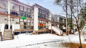 A building with multiple floors, large windows, and a staircase leading to the upper levels. - Updated condo near ski resort with heated pool, hot tub, fireplace, balcony, W&D (Olympic Valley)