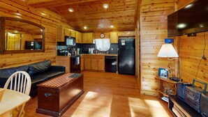 Een houten chalet van binnen met keuken, eethoek en woonkamer.