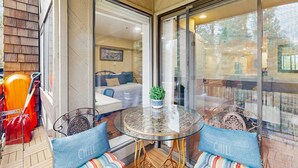 Ein verglaster Balkon mit einem runden Tisch, zwei gepolsterten Stühlen und einem Blumentopf.