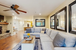 A living room with a sectional sofa, a coffee table with flowers, a fireplace, and a ceiling fan. - Mountain Retreat: Cozy condo at Ski Way Ridge for your Lake Tahoe escape (Incline Village)
