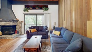 A living room with a stone fireplace, two sofas, a coffee table, and a wooden ceiling.