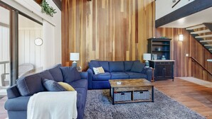 A modern living room with a blue sofa set, a wooden coffee table, and a staircase.