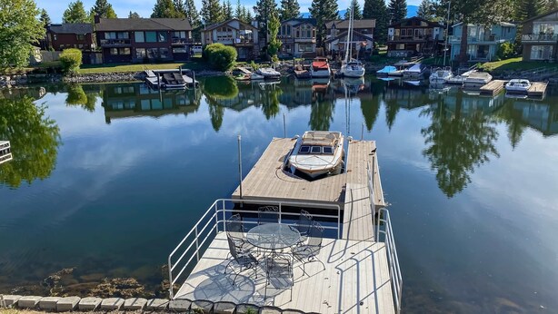 A marina with docked boats, a wooden pier, and residential buildings in the background. - Charming Tahoe Keys Waterfront Retreat with Private Dock, Pool Table (South Lake Tahoe)