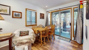 Une pièce chaleureuse avec une table à manger en bois, des chaises, un canapé et une fenêtre avec des stores.