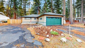 A house with a garage, surrounded by a forest. - Relaxing Dog-friendly home with gas grill & private fenced yard - close to marina (South Lake Tahoe)