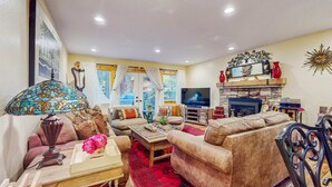 A living room with a sofa, armchair, coffee table, TV, fireplace, and decorative items. - Relaxing Dog-friendly home with gas grill & private fenced yard - close to marina (South Lake Tahoe)