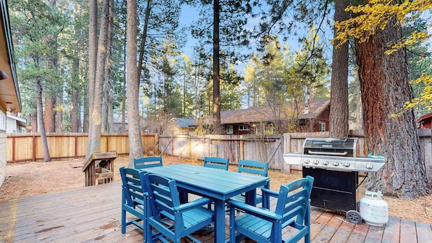 A wooden deck with a blue table and chairs, a grill, and a wooden fence. - Relaxing Dog-friendly home with gas grill & private fenced yard - close to marina (South Lake Tahoe)