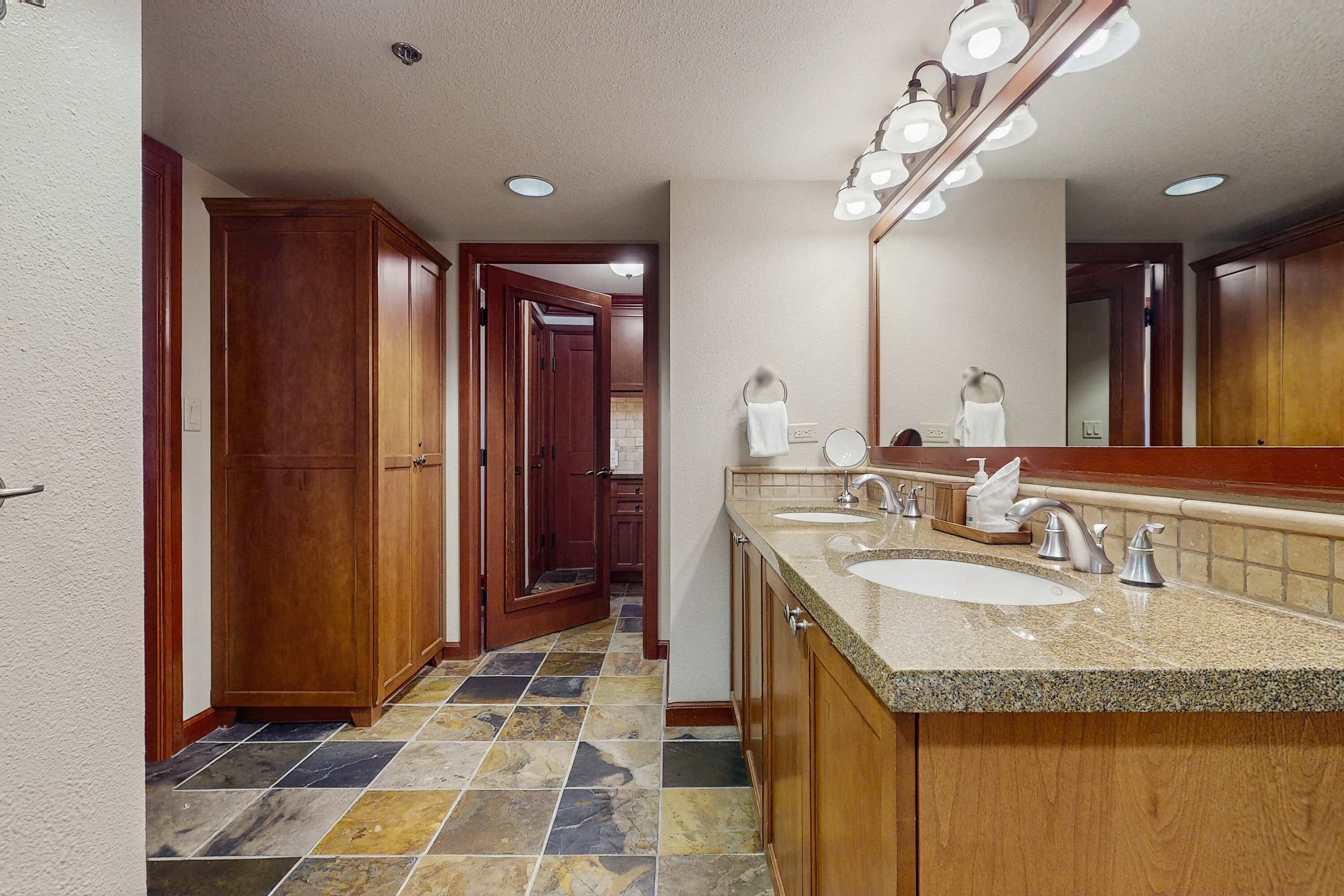 A bathroom with two sinks, a large mirror, and wooden cabinets.