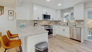 Una cucina moderna con mobili bianchi, piano cottura in acciaio inossidabile e lavastoviglie.