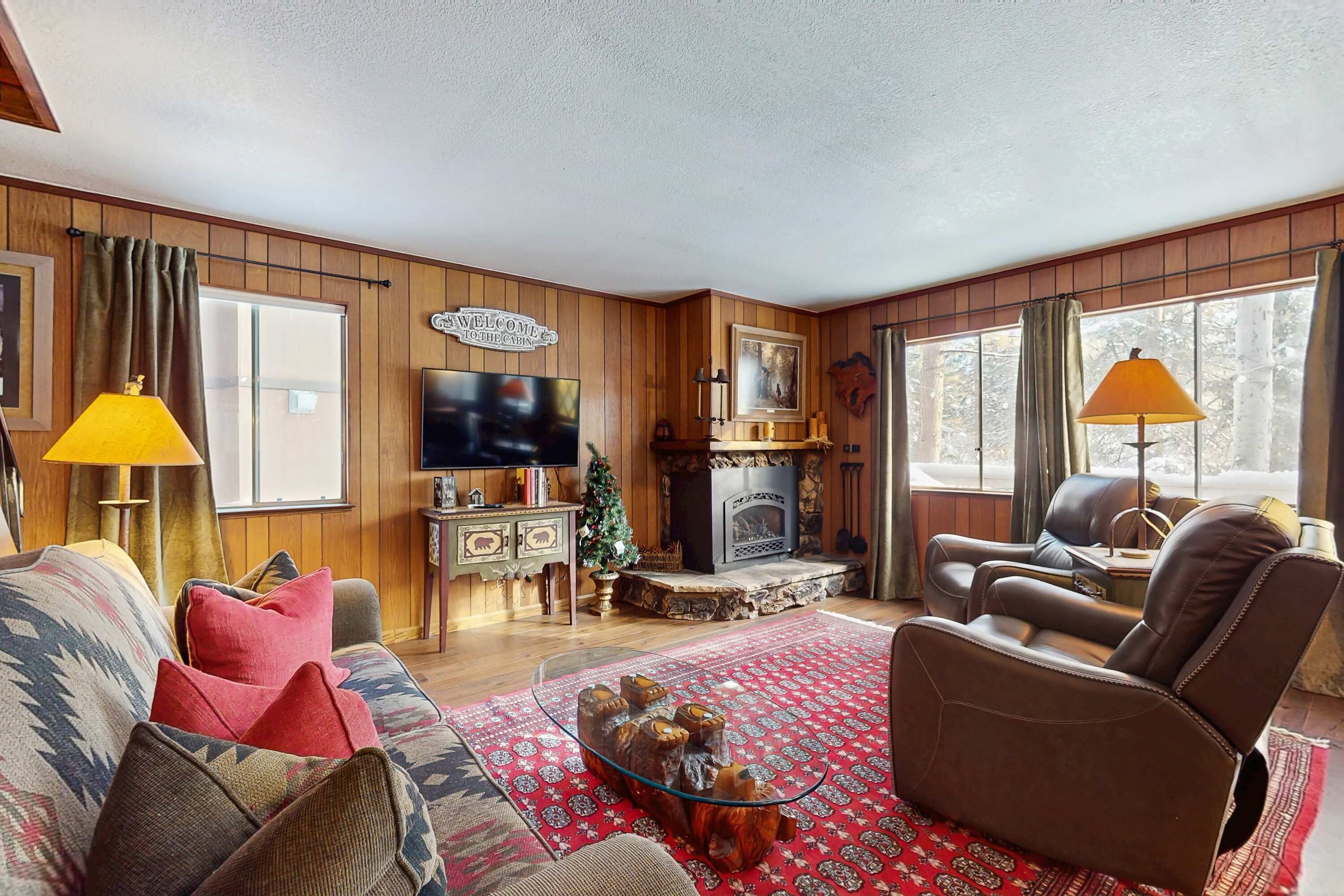 A cozy living room with a fireplace, leather sofa, and a television.