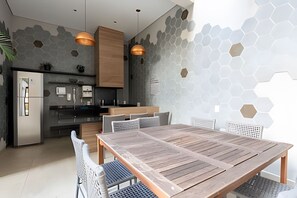 Uma cozinha moderna com ilha central, iluminação pendente e área de refeições com mesa e cadeiras de madeira.