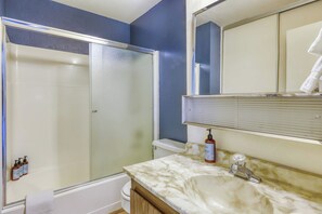 Une salle de bain équipée d’une douche, de toilettes, d’un lavabo et d’un miroir.