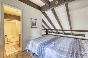 Une chambre à coucher avec un lit, un tableau encadré au mur et une structure de poutres en bois au plafond.