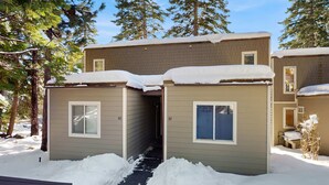 A two-story building with a snow-covered roof and a narrow entrance. - Cozy and Convenient Condo with Fireplace, Deck, W&D, Close to Town, Lake, Trails (Tahoe City)