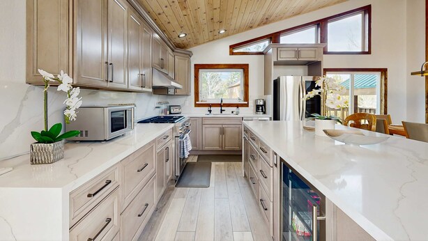 A modern kitchen with wooden cabinets, a large island, and a view of the outdoors. - Pristine Family and Dog Friendly Mountain Home with Deck, BBQ, W&D (Truckee)
