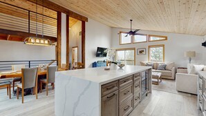 A spacious living area with a large island, wooden ceiling, and a television mounted on the wall. - Pristine Family and Dog Friendly Mountain Home with Deck, BBQ, W&D (Truckee)