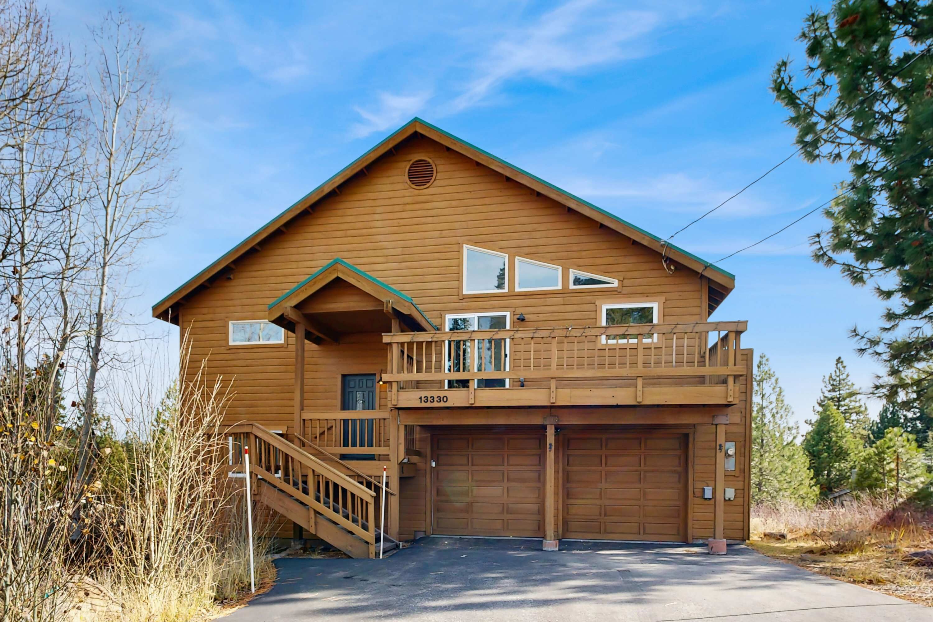 A two-story wooden house with a balcony, a garage, and a visible address number.
