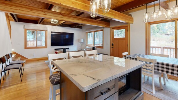 Una cocina amplia con una isla grande, vigas de techo de madera e iluminación colgante.