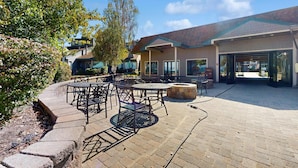 An outdoor patio area with tables and chairs, a stone fire pit, and a building entrance. - Amazing amenities, pool views, and a privileged location near Heavenly await (South Lake Tahoe)