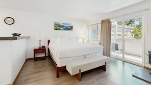 A hotel room with a bed, a bench, a nightstand, a clock, a painting, and a view of the outside. - Amazing amenities, pool views, and a privileged location near Heavenly await (South Lake Tahoe)