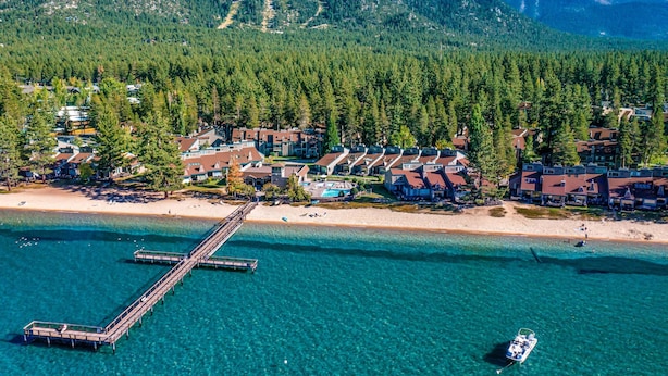 An aerial view of a coastal resort with a pier, beachfront properties, and a mountainous backdrop. - Amazing amenities, pool views, and a privileged location near Heavenly await (South Lake Tahoe)