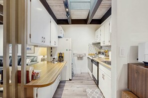 A narrow kitchen with white cabinets, a wooden countertop, and a tiled backsplash. - Cozy Family-Friendly Condo with Fenced Yard, Deck, BBQ, Walk to Shops (Incline Village)
