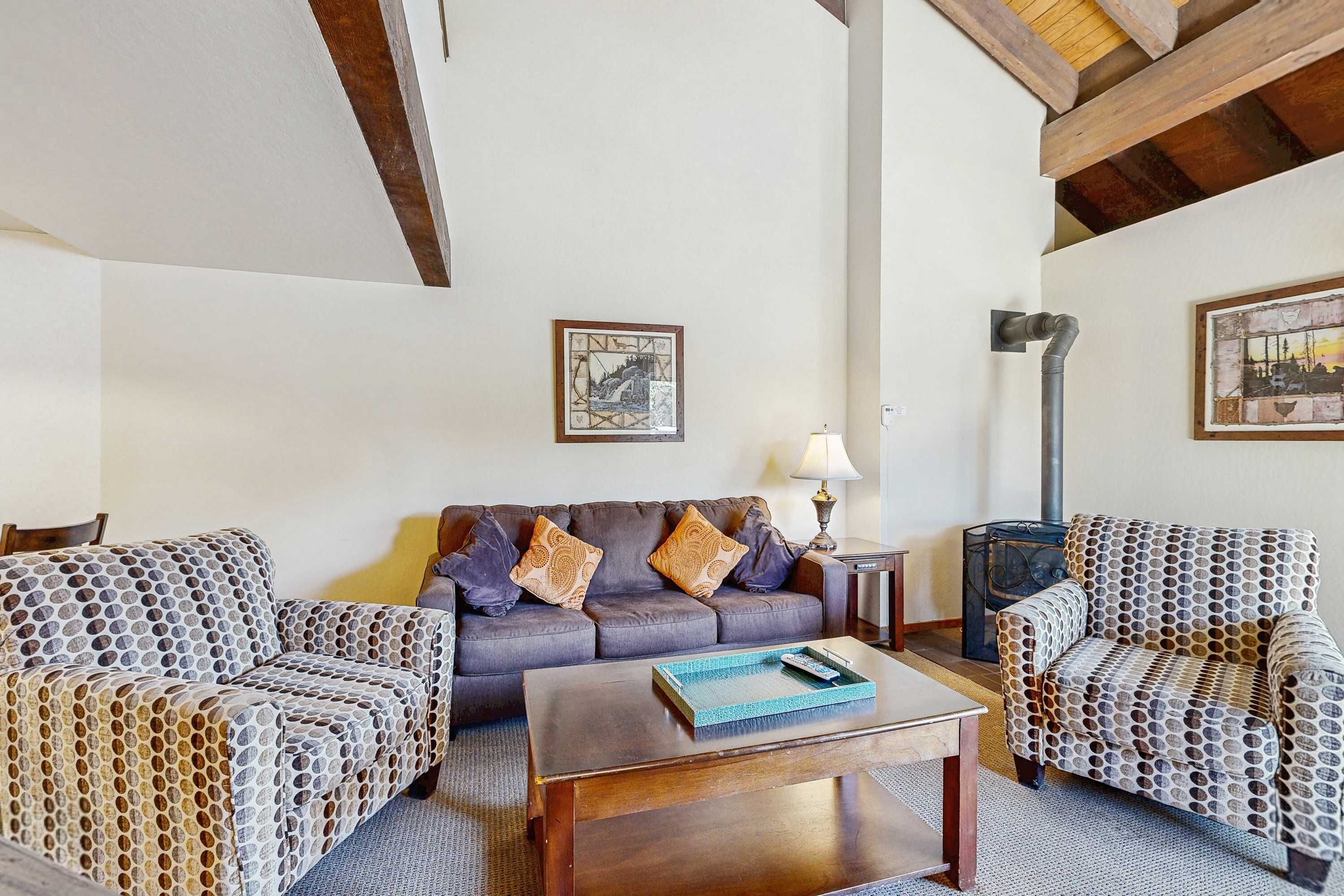 A living room with a sofa, two patterned armchairs, a coffee table, and a fireplace.