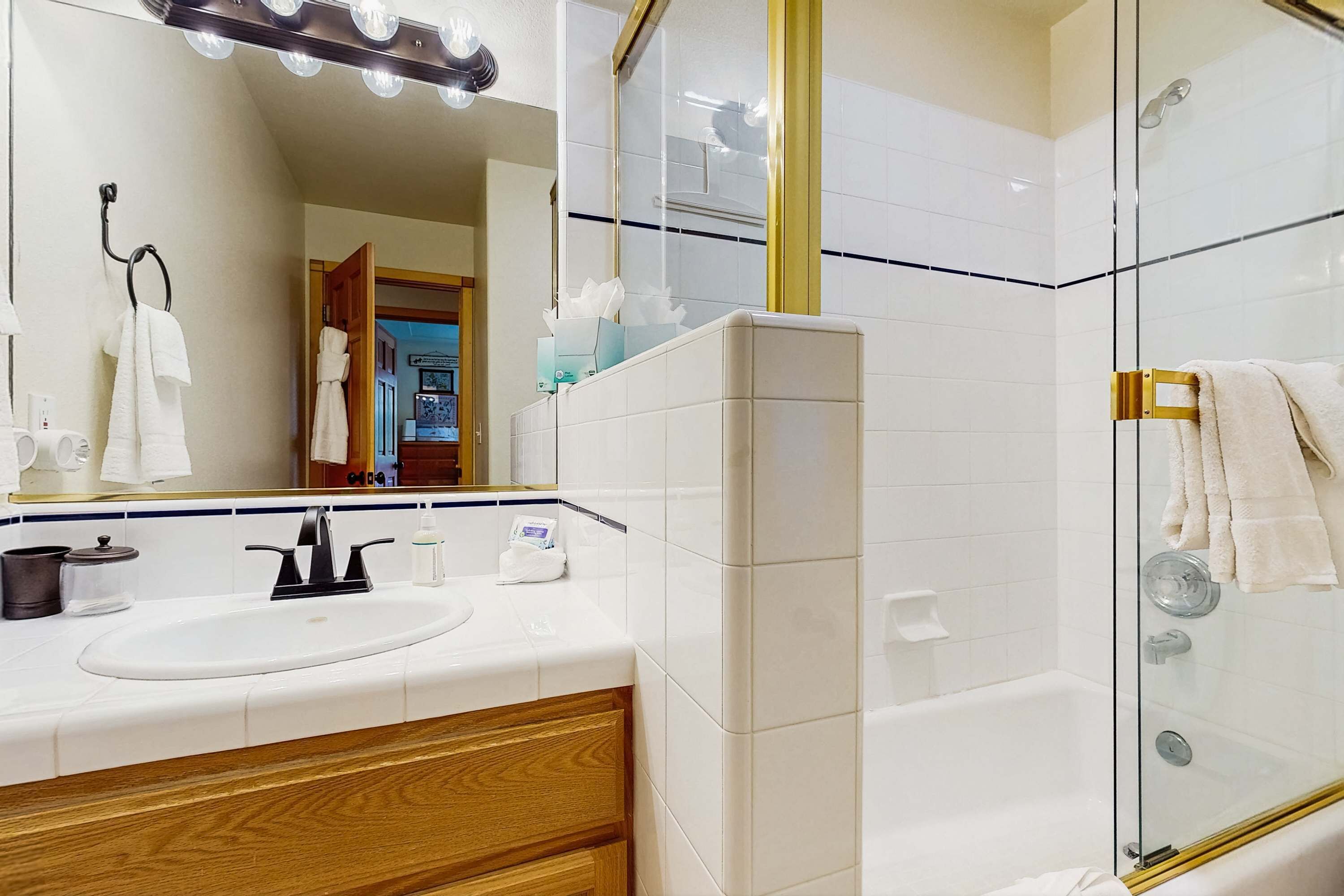 Un baño moderno con ducha de vidrio, tocador con lavamanos y espejo con iluminación.
