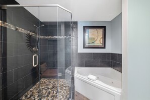 A modern bathroom with a glass-enclosed shower, a white bathtub, and a framed abstract painting on the wall. - Lighthouse 1615 by Liquid Life (Gulf Shores)