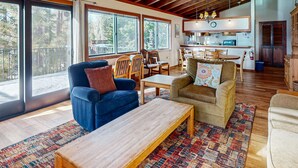 A spacious living area with a large wooden table, comfortable seating, and a kitchen in the background. - Homey Family Condo with Shared Pool, Hot Tub, Tennis & Lovely Lake Views (Tahoe City)