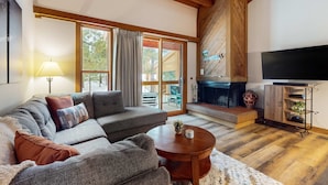 A cozy living room with a sofa, a coffee table, a fireplace, and a television. - Cozy townhouse with pool access, board games, and fireplace - near skiing (Northstar - Truckee)