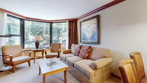 A corner living room with a sofa, chairs, a coffee table, and a lamp. - Everline Resort & Spa Ski-in-ski-out condo, pools, tennis, ice rink, & gym (Olympic Valley)