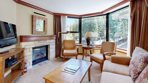 A corner living room with a fireplace, television, and seating area. - Everline Resort & Spa Ski-in-ski-out condo, pools, tennis, ice rink, & gym (Olympic Valley)