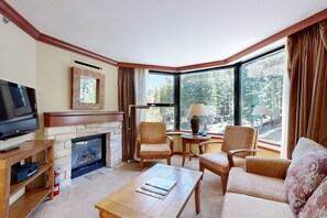 A corner living room with a fireplace, television, and seating area. - Everline Resort & Spa Ski-in-ski-out condo, pools, tennis, ice rink, & gym (Olympic Valley)