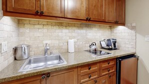 A kitchen with wooden cabinets, a granite countertop, a stainless steel sink, and a coffee maker. - Everline Resort & Spa Ski-in-ski-out condo, pools, tennis, ice rink, & gym (Olympic Valley)