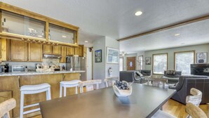 Un'ampia cucina con mobili in legno, una zona pranzo con un tavolo grande e un soggiorno con divano e televisore.