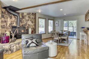 A living room with a stone wall, a fireplace, a leather sofa, a dining area, and a view through large windows.