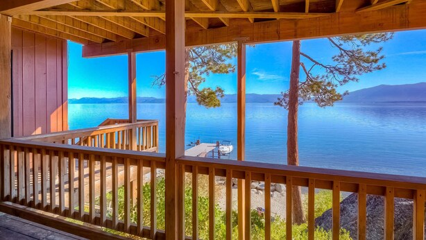 Um deck de madeira com vista para um lago calmo e montanhas.