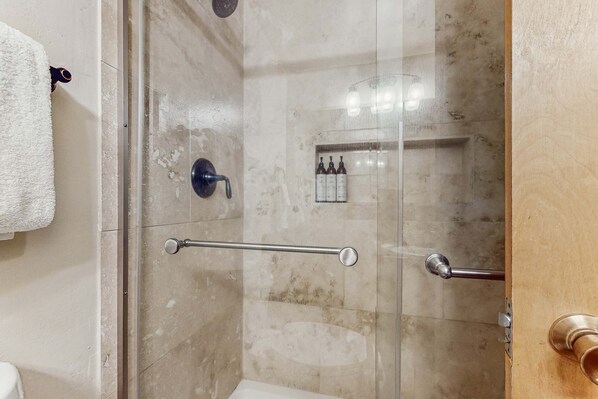 A glass-enclosed shower with a handrail, a towel rack, and a shelf with toiletries. - Second-level studio with mountain views - pool & covered balcony (Tahoe City)
