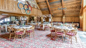 Ein Restaurant mit Holzbalkendecken, runden Tischen und Stühlen mit roten Kissen.