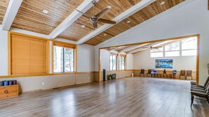 Ein geräumiges Zimmer mit Holzböden, Deckenventilatoren, großen Fenstern und einer Sitzecke mit Stühlen.