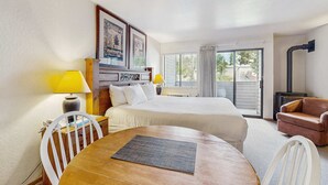 Ett hotellrum med en säng, två sänglampor, ett bord med en stol, en soffa och utsikt över omgivningarna genom en skjutdörr.